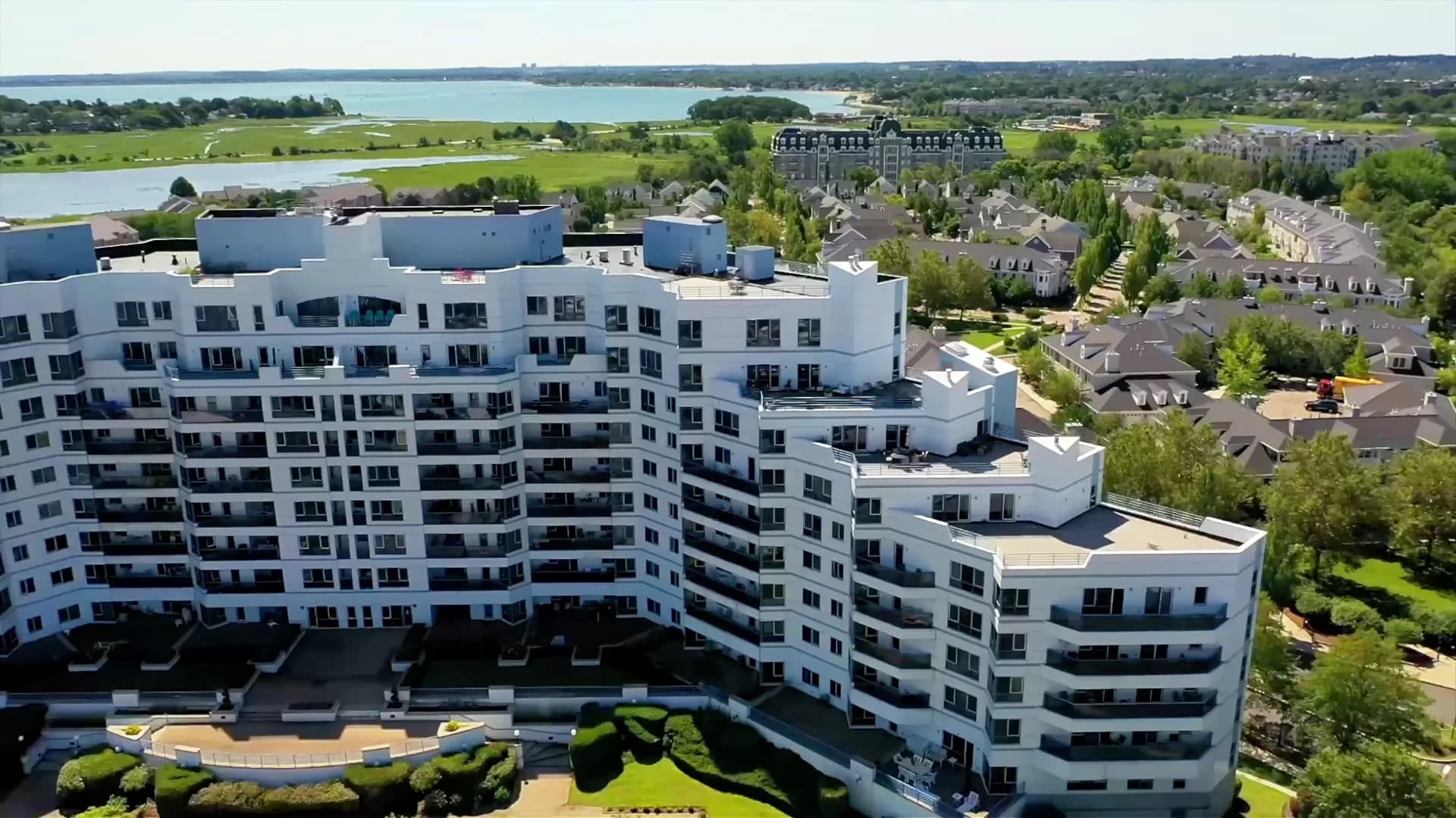 Aerial view of a white waterfront building with flat commercial roofs.